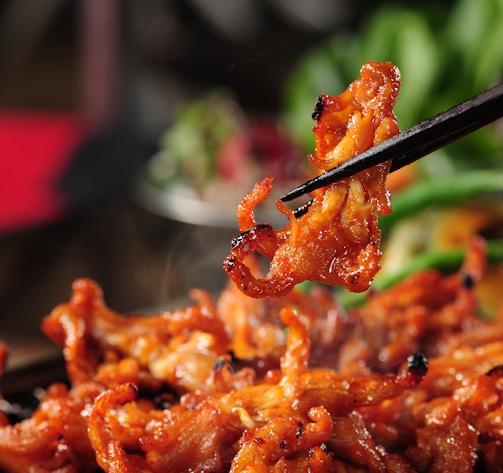 a close up of a person holding chopsticks over some food